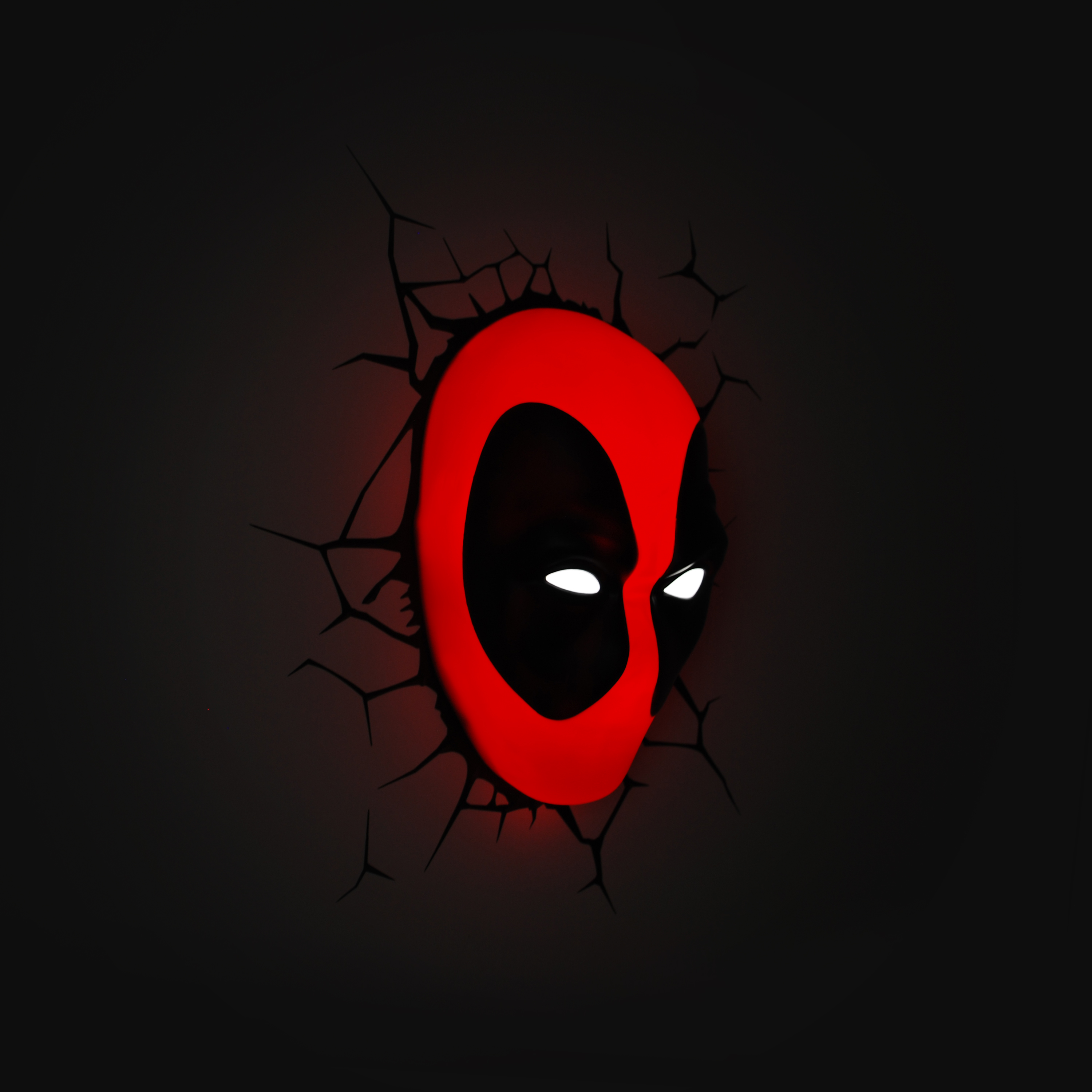 Deadpool mask wall light glowing red through a cracked wall