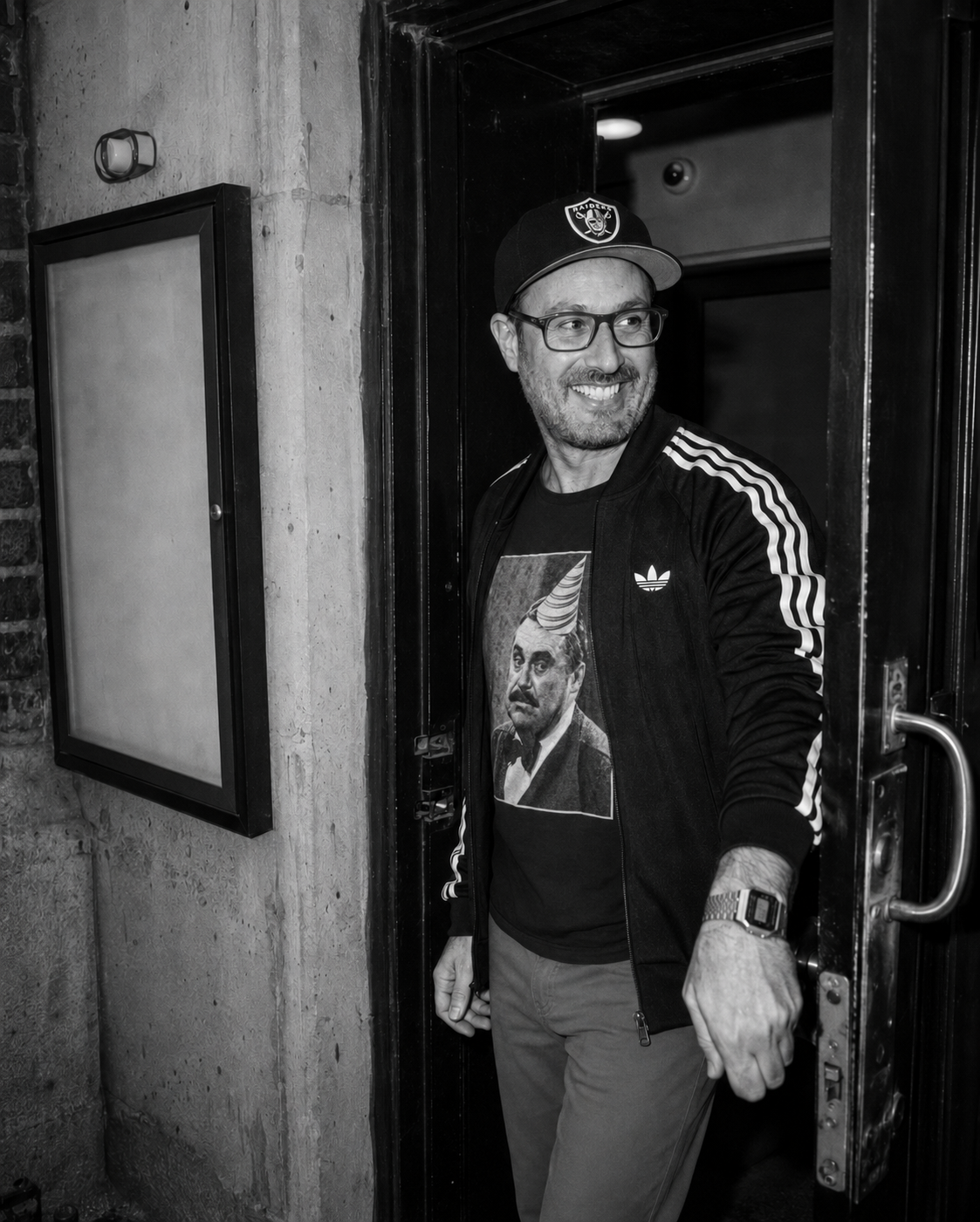 Ben Corber walking through a doorway in a black-and-white candid photograph